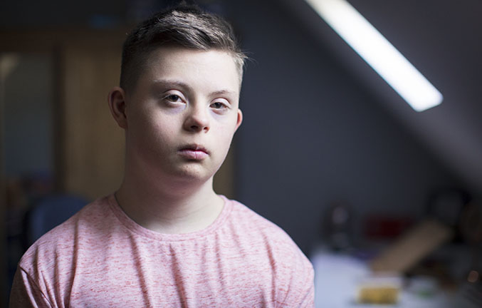 Portrait of a frowning teenage boy with Down syndrome