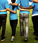 Rear view of four people standing on lawn linking arms