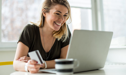 women holding a credit card with coffee on laptop